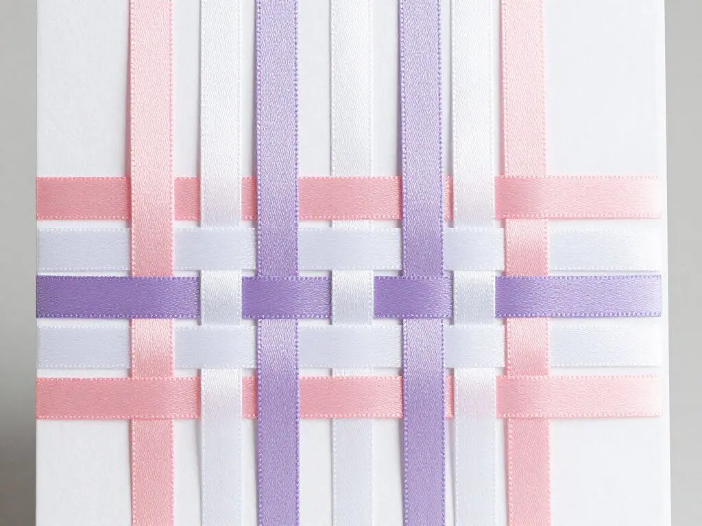 Card front with colorful ribbons woven through slits in geometric pattern