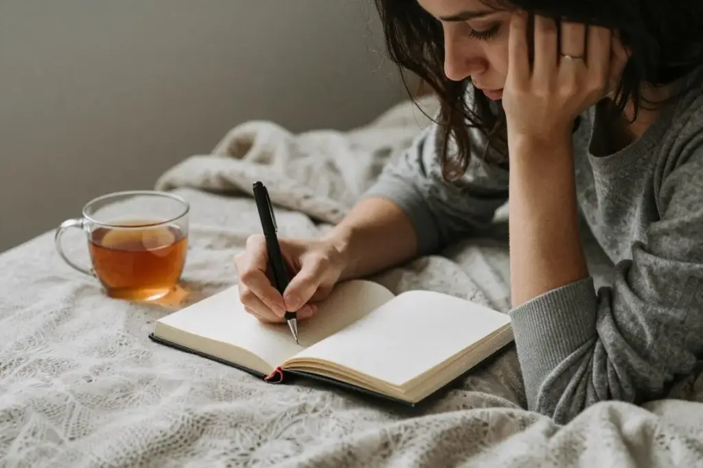 Person journaling emotions in a cozy setting