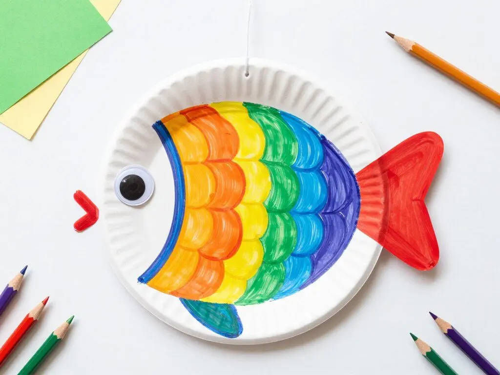 completed paper plate rainbow fish craft with colorful scales and googly eyes