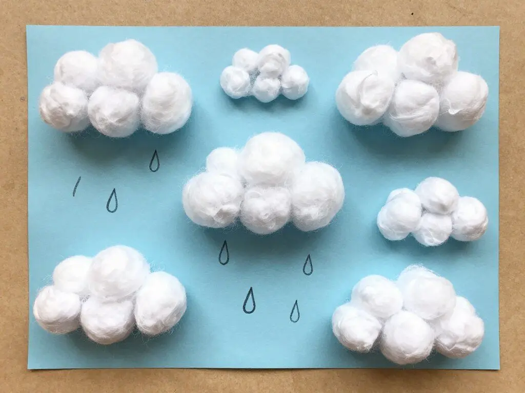 cotton ball cloud craft on blue construction paper with white fluffy clouds