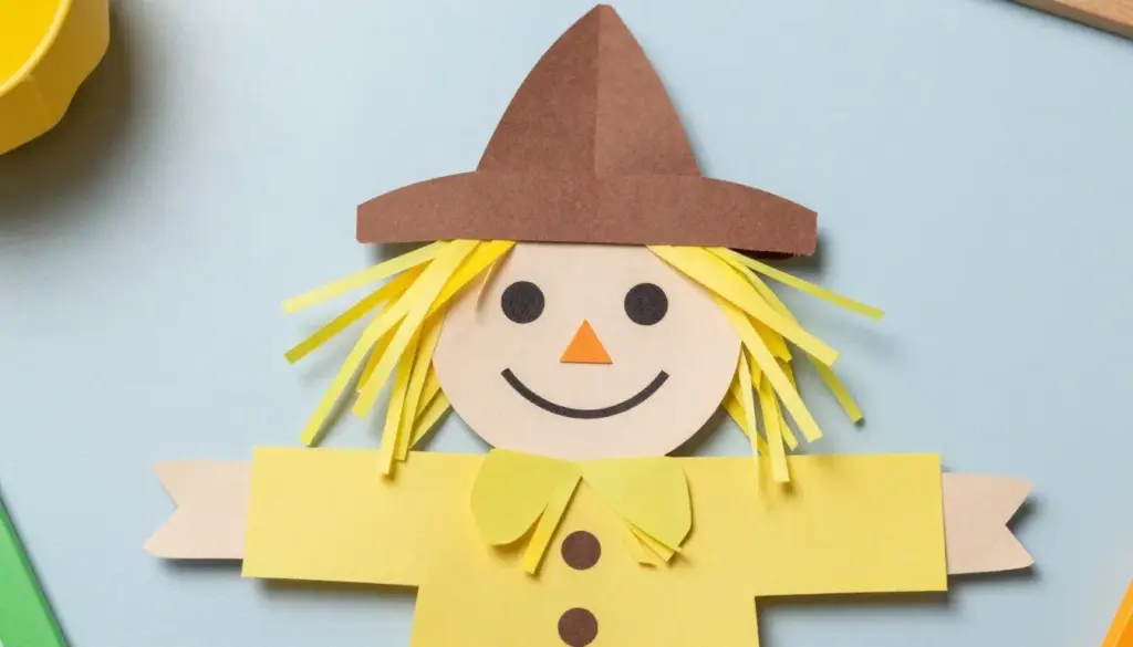 A cut-out paper scarecrow face featuring a floppy hat and yellow paper straw hair