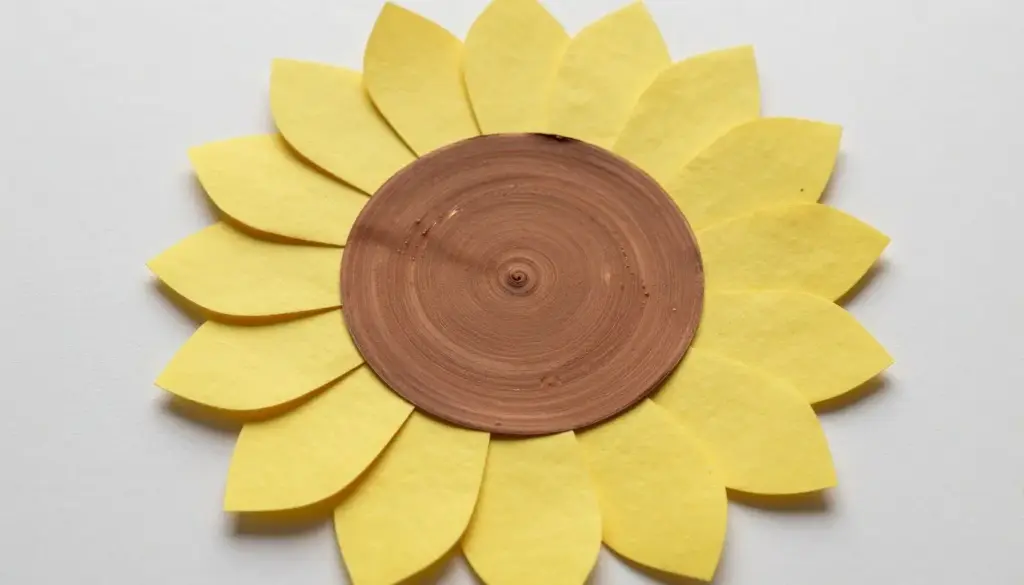 A paper plate sunflower craft with cut petals and a textured brown seed center