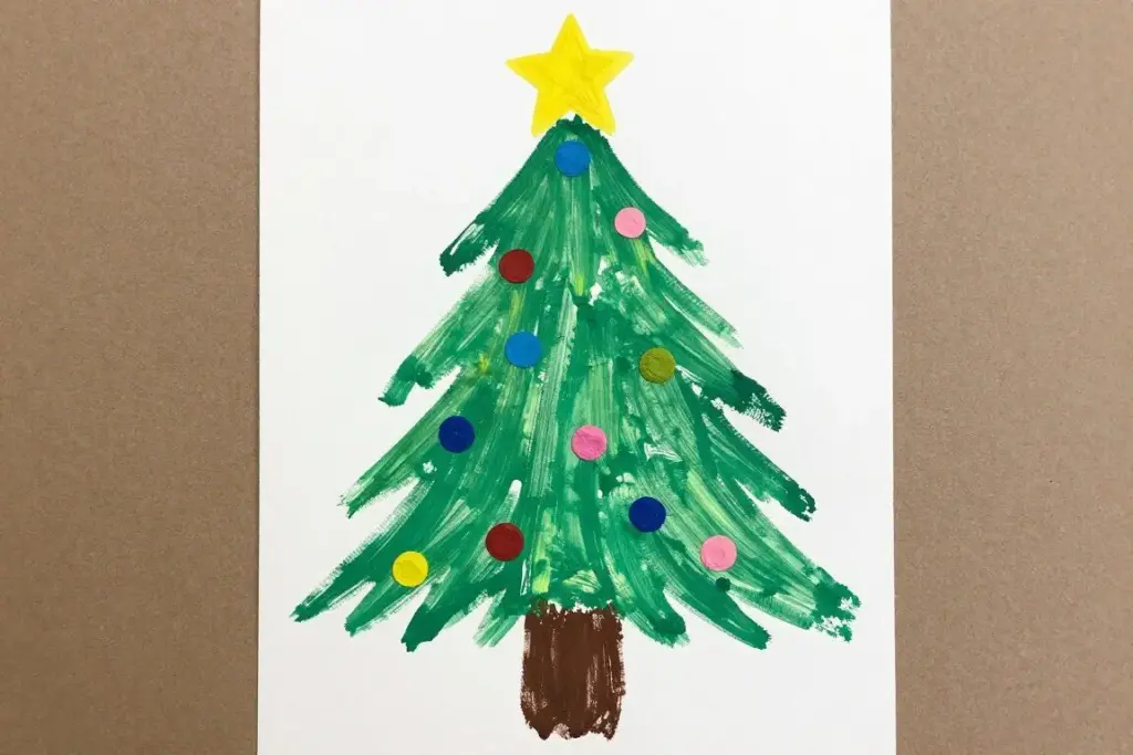 Children handprint Christmas tree craft on white paper with painted ornaments