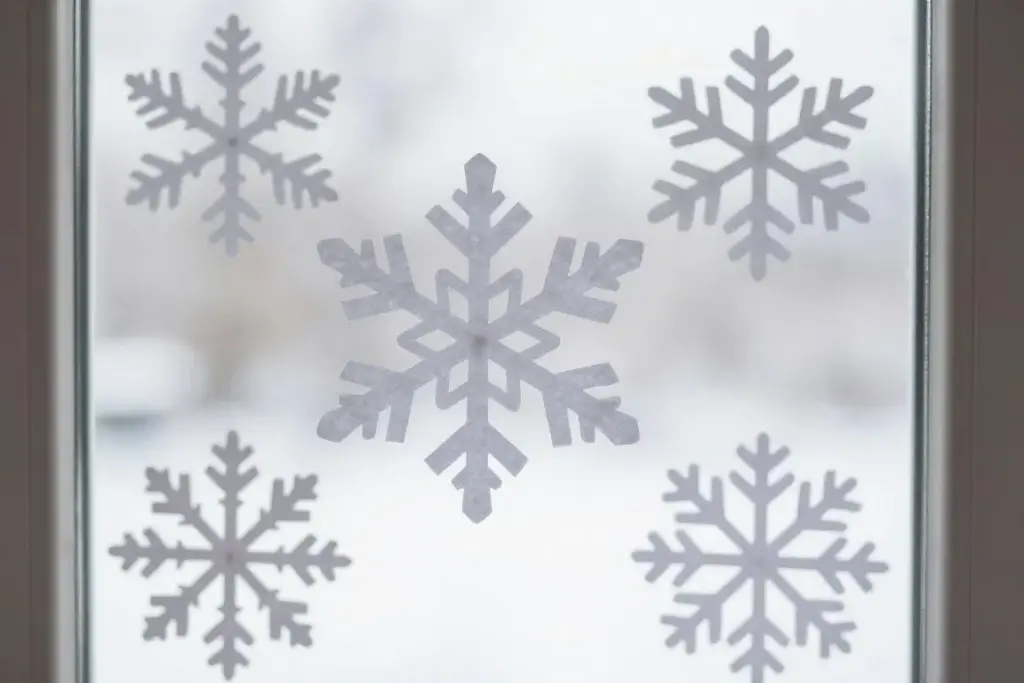 Delicate paper snowflakes cut from white paper hanging in a window